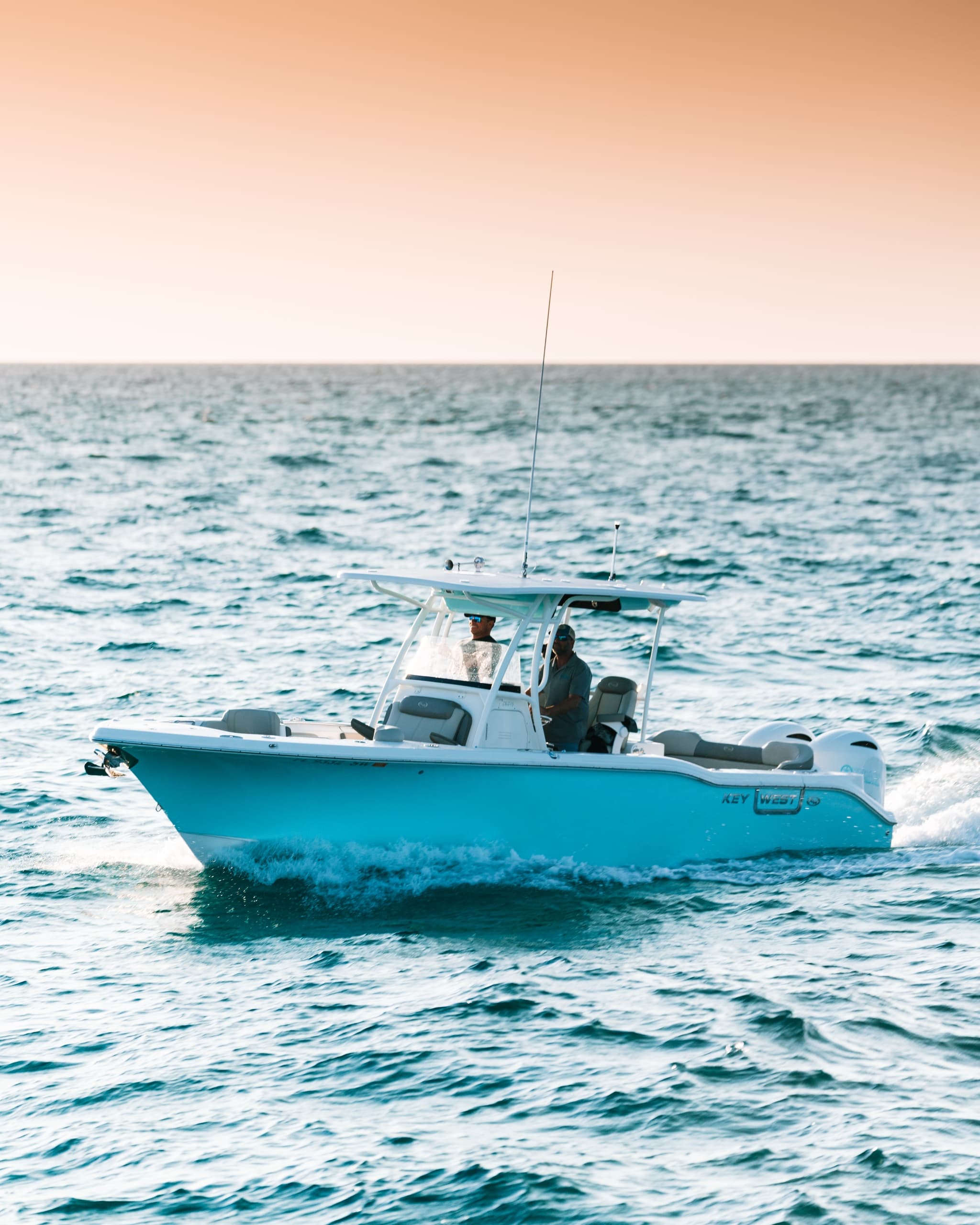 Center console boat speeding through blue ocean near sunset