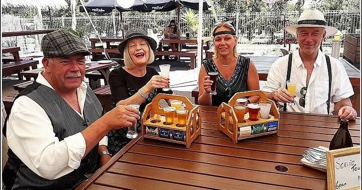 Group enjoying craft beer tasting on outdoor picnic table in vineyard