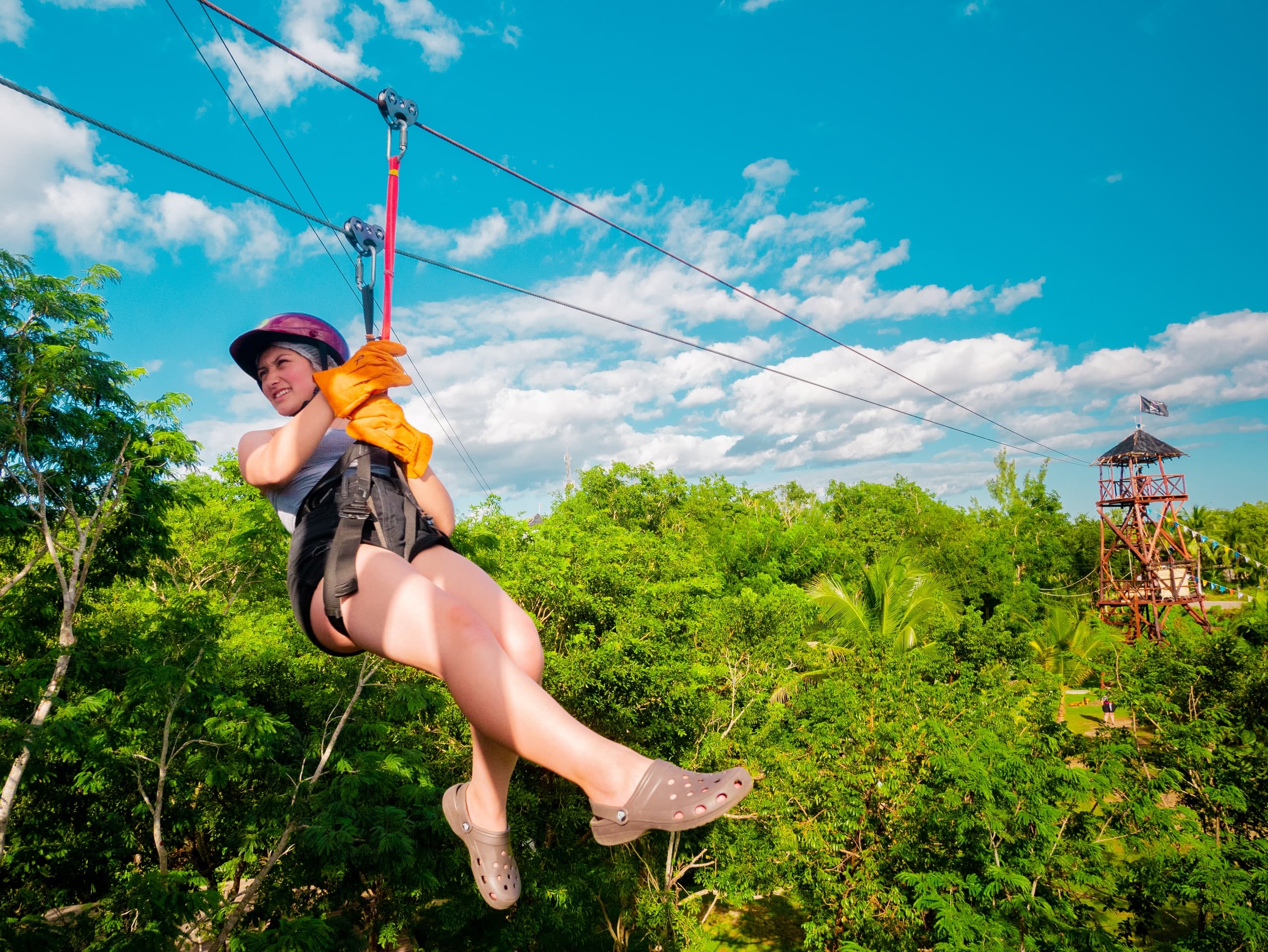 Person ziplining over tropical forest canopy in Cozumel