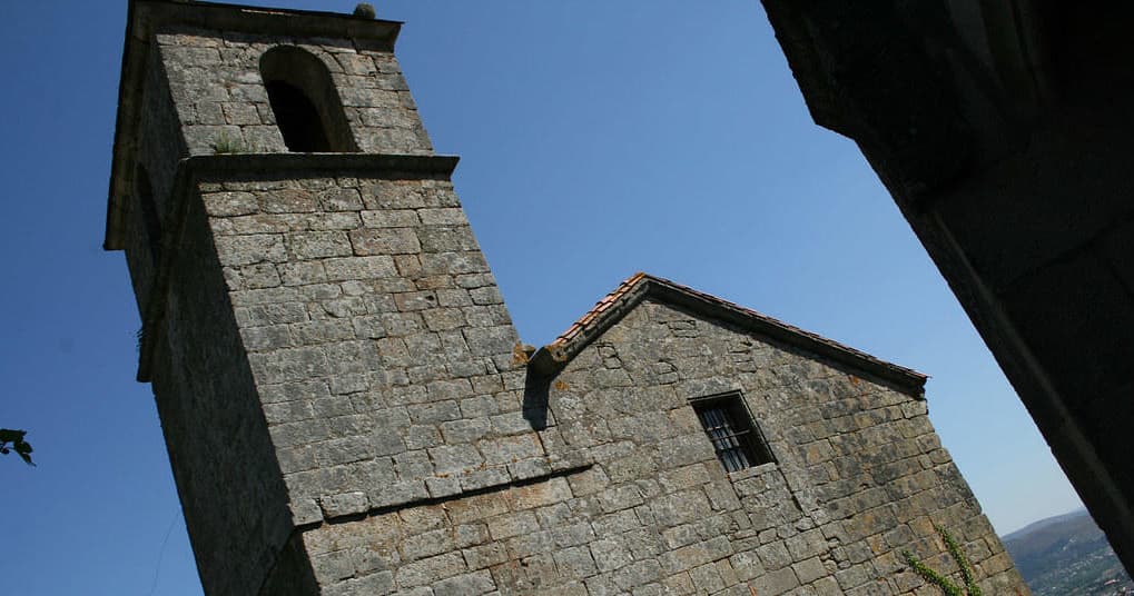 Historic stone church tower against blue sky, cultural site visit