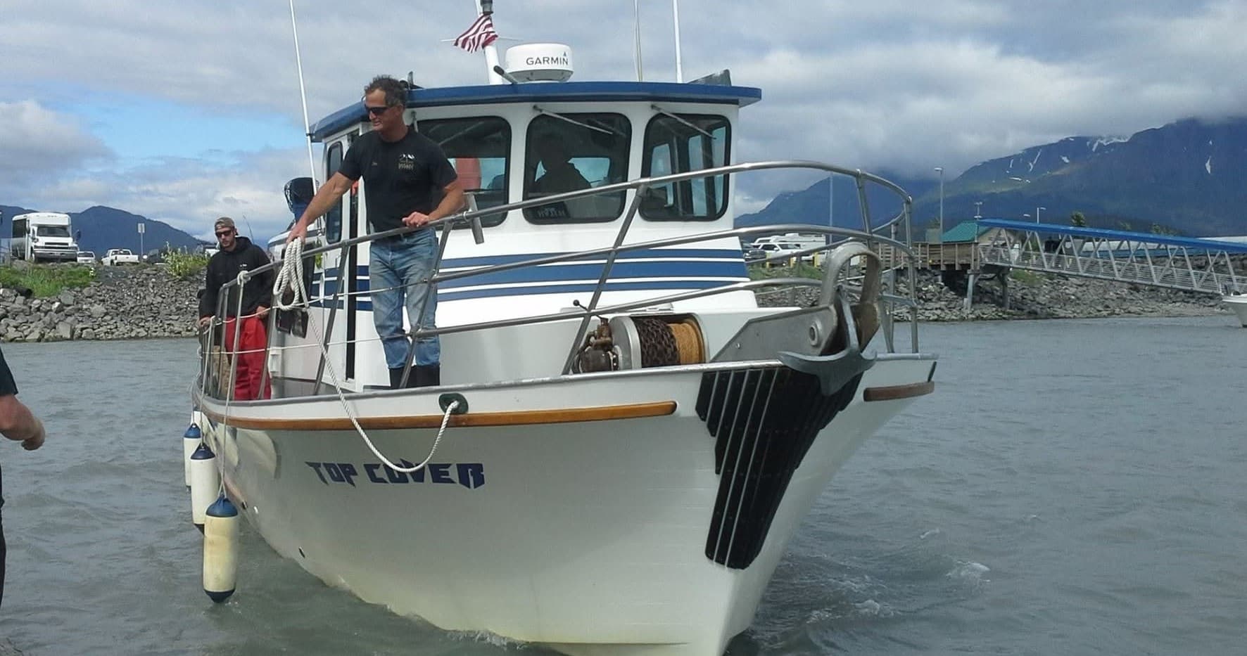 Coastal charter boat docking near Kodiak harbor with crew
