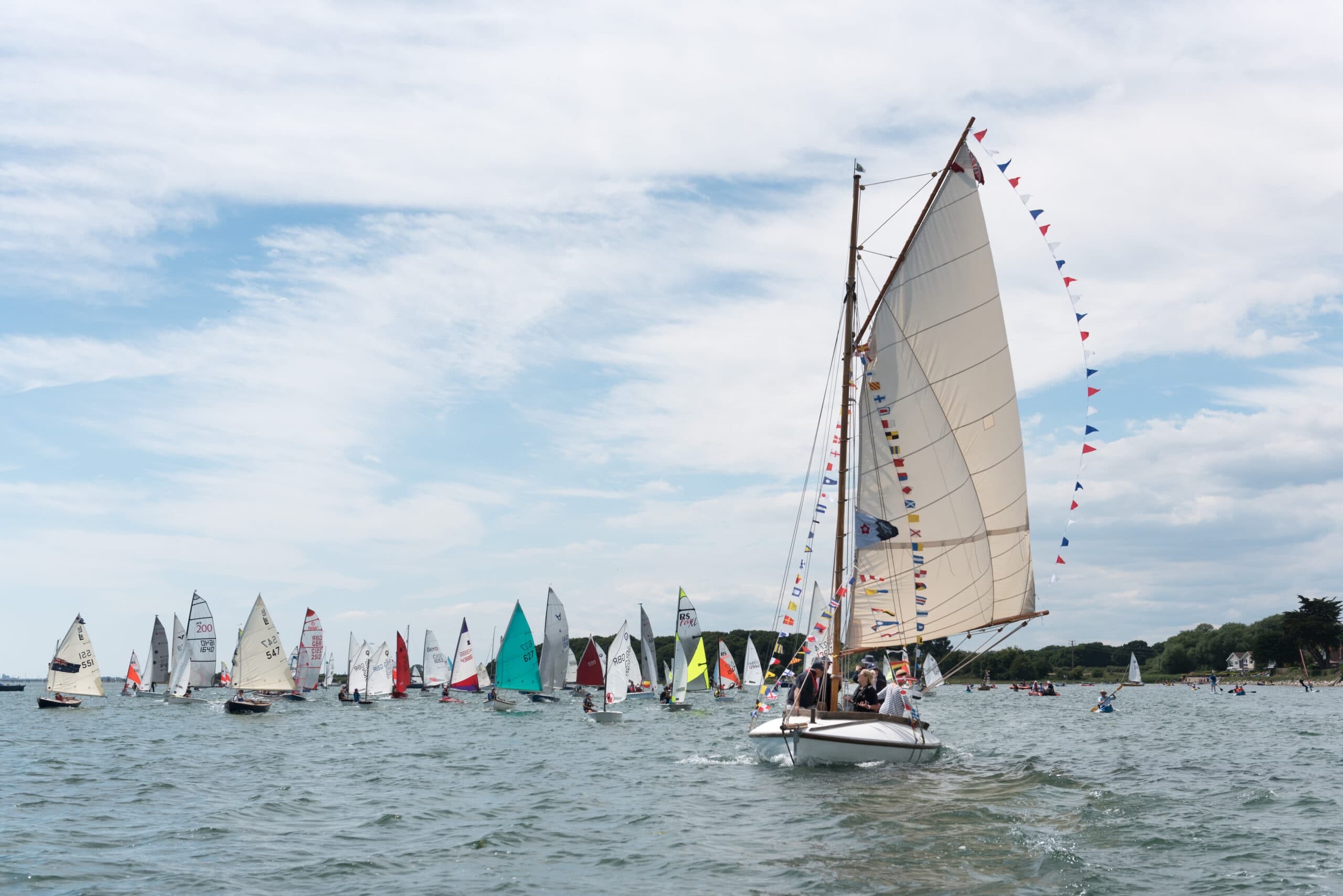 Sailboat racing in coastal waters under cloudy sky