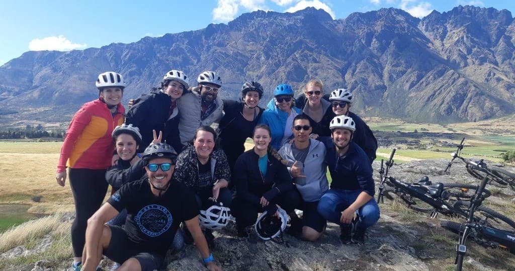 Group of cyclists posing on hillside with rugged mountain view