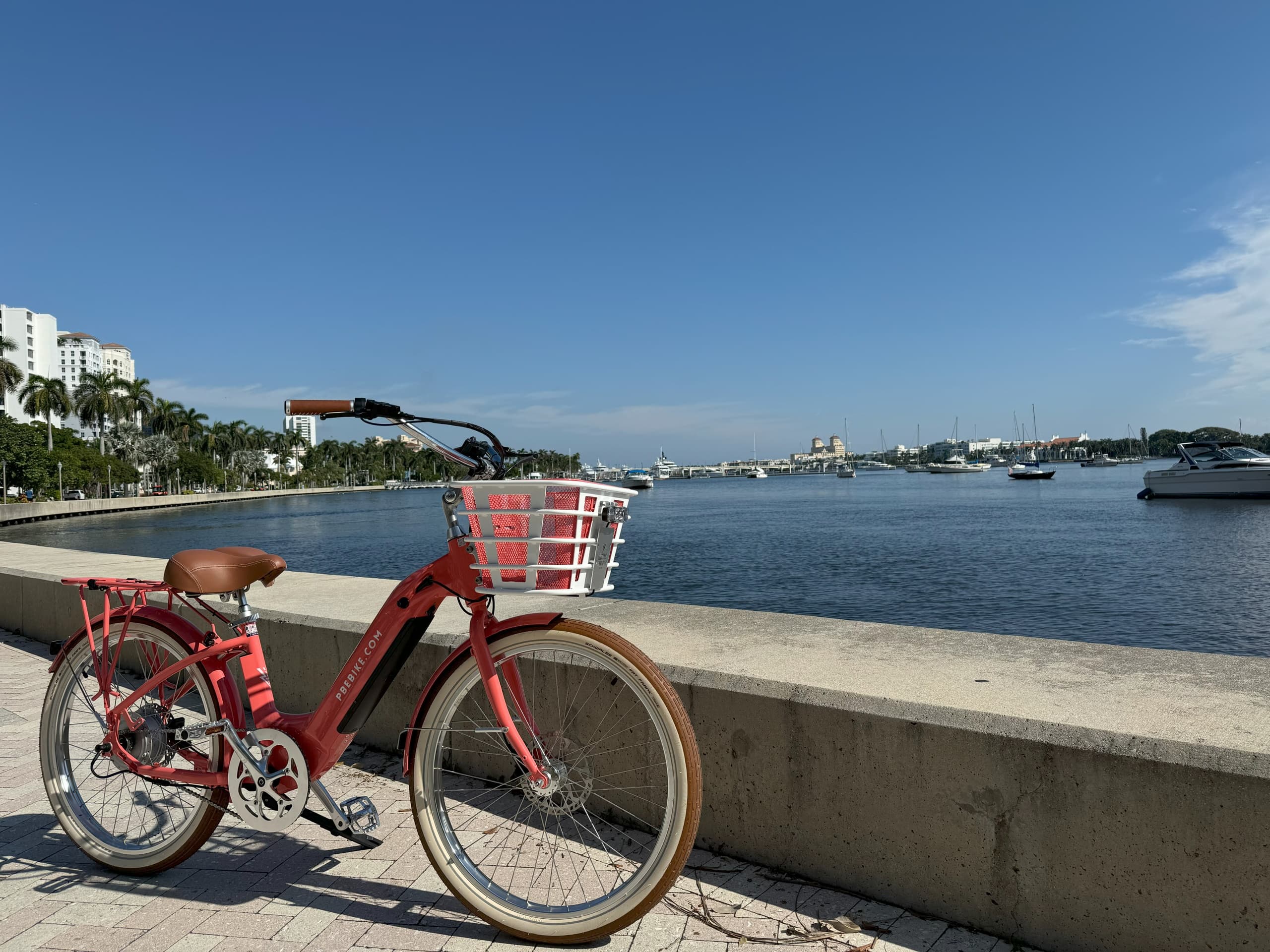 Red rental bike parked on sunny waterfront promenade by marina