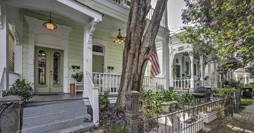 Historic New Orleans shotgun house porches on shaded street