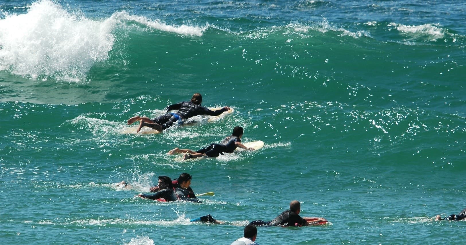 Surfers paddling into large breaking waves off Biscarrosse coast