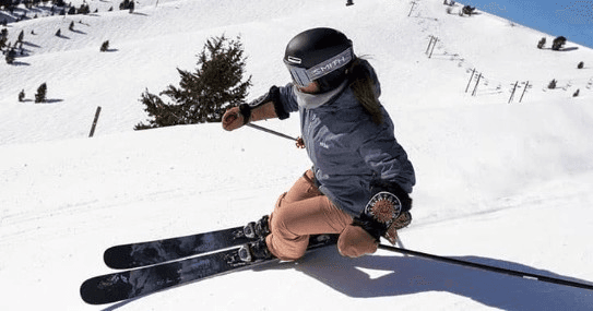 Skier carving deep snow on mountain slope with clear blue sky