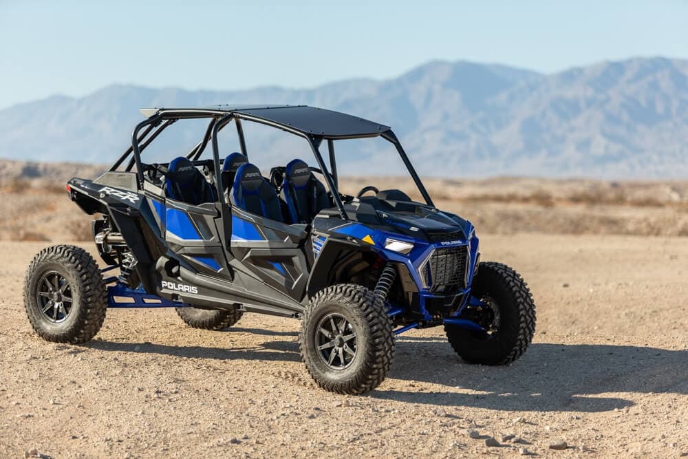 Blue off-road UTV in desert with open sky and rugged terrain
