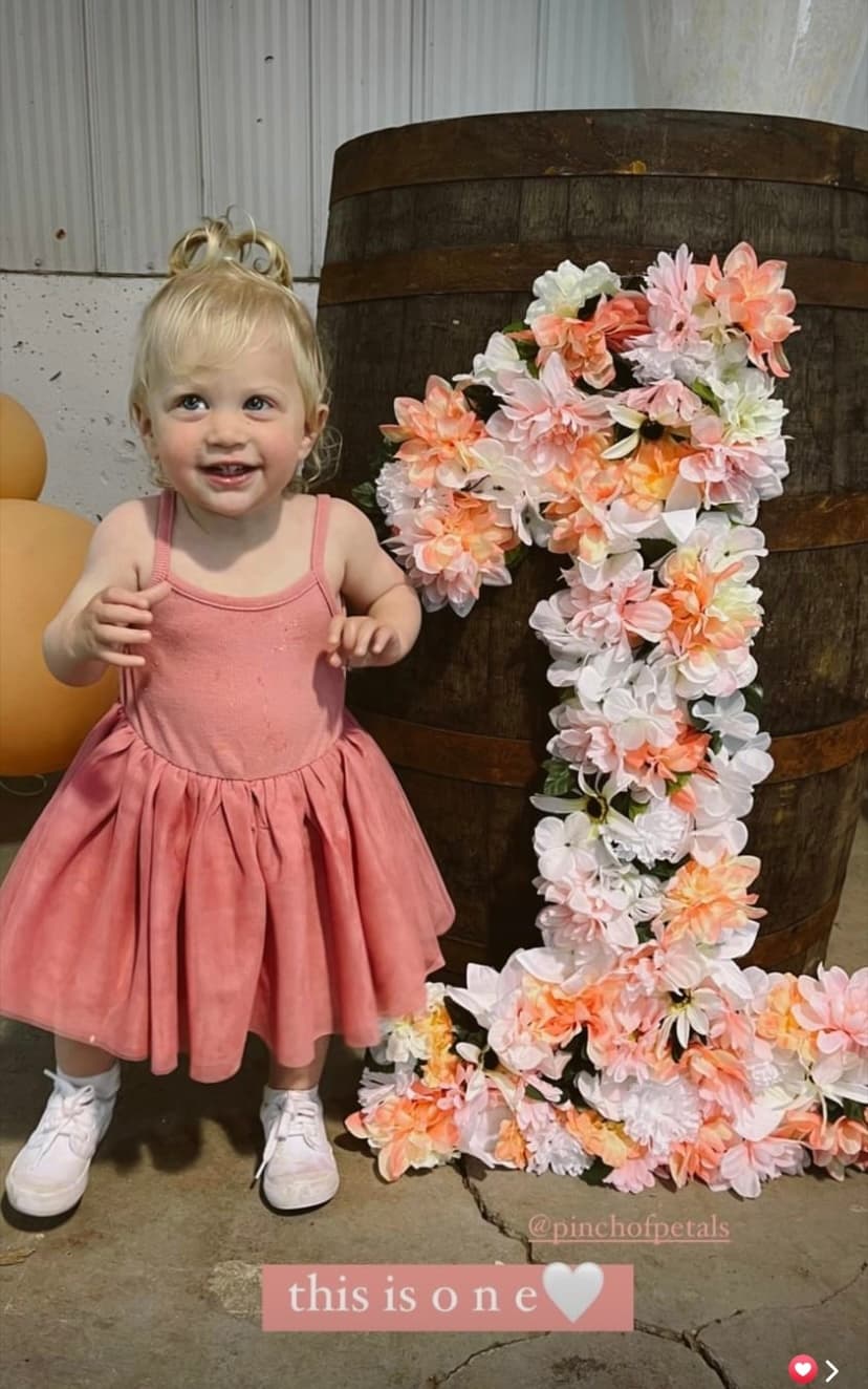 Toddler posing with floral number one prop at indoor birthday
