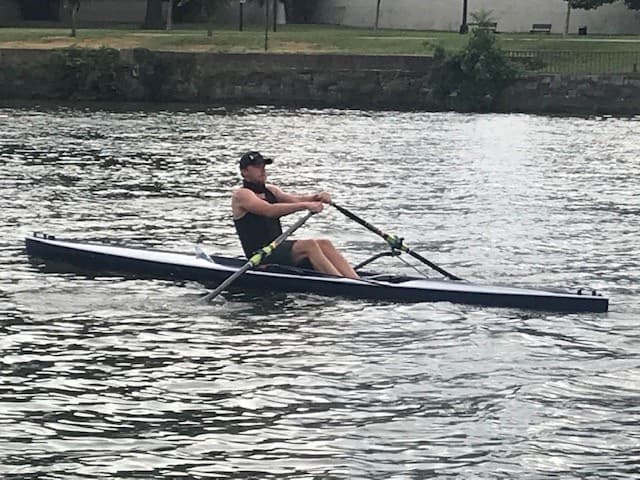 Single sculler rowing strong strokes on city river