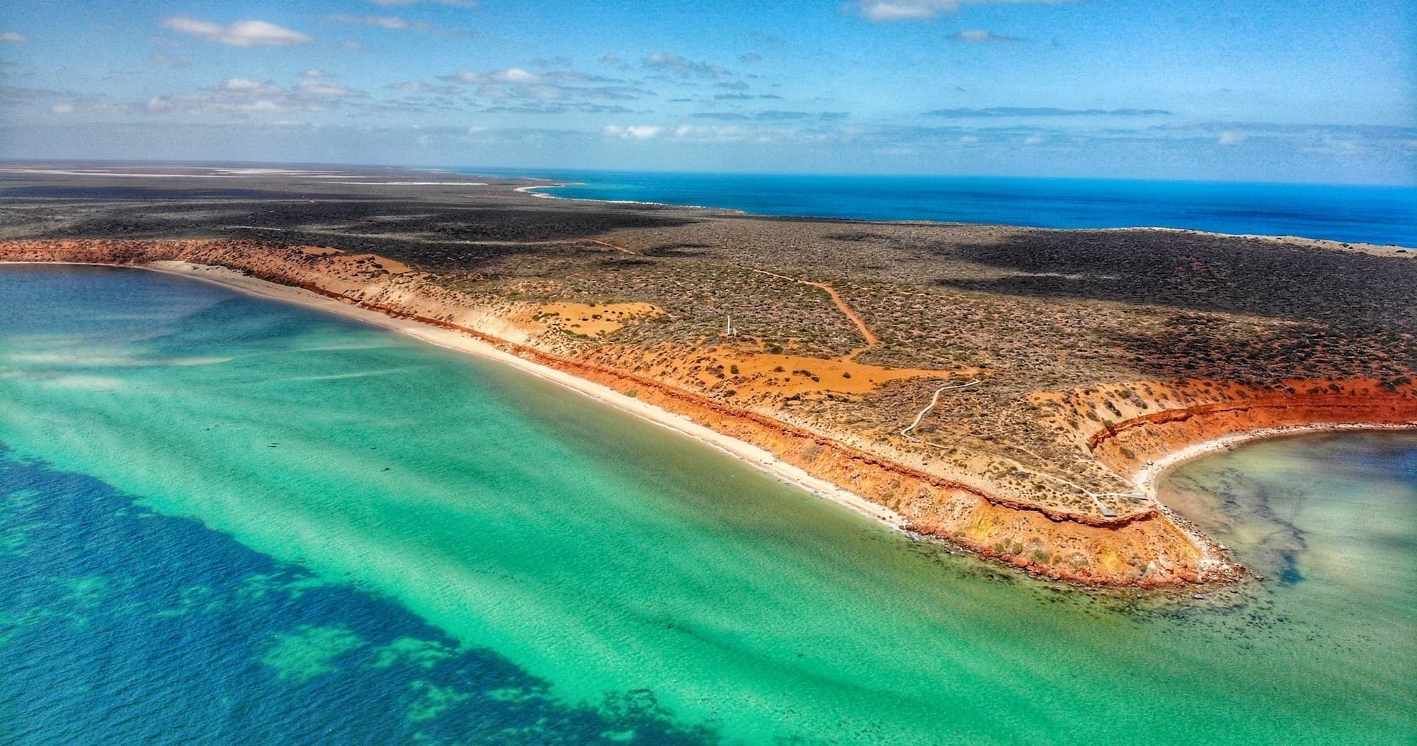 Aerial coastal landscape of turquoise bay and red cliff shoreline