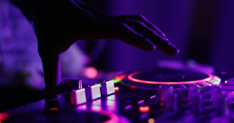 Nighttime DJ controller illuminated with purple club lighting