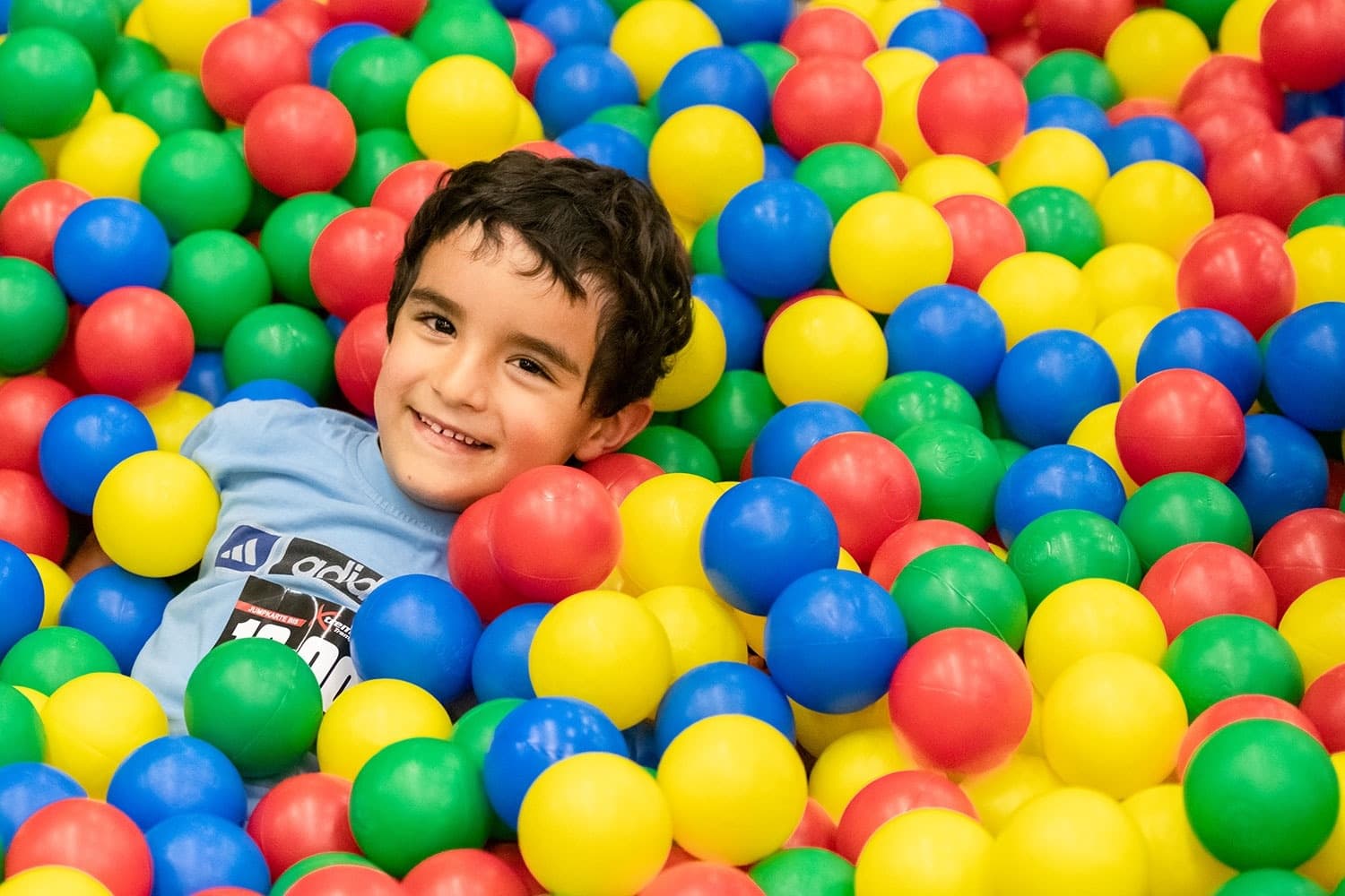 Child smiling in colorful indoor ball pit at play center