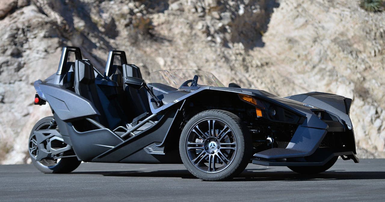 Black Slingshot parked with rocky canyon backdrop, profile view
