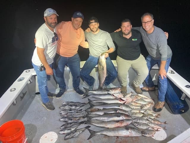 Group of anglers with night's catch spread on deck after deep-sea trip