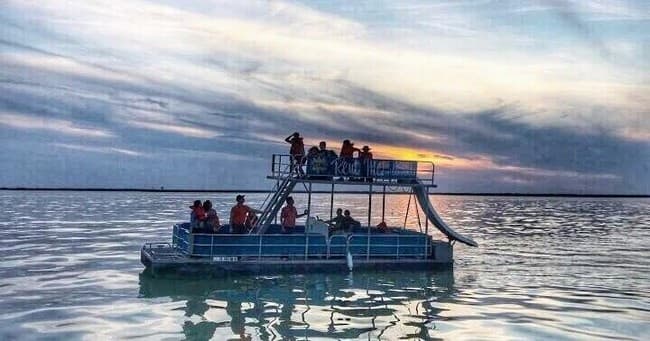 Sunset cruise on pontoon boat with passengers on tranquil lake