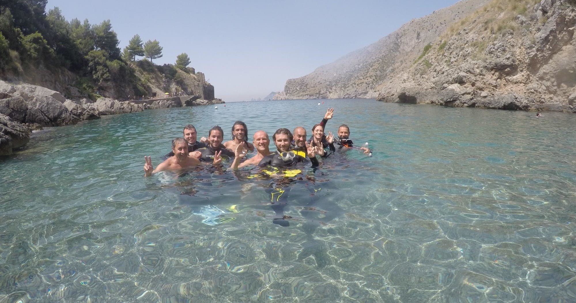 Group snorkeling in clear coastal cove with rocky cliffs