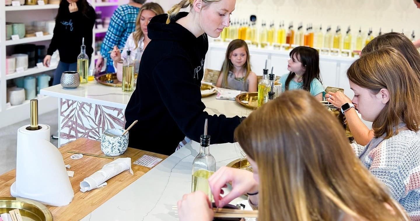 Instructor guiding candle-making workshop participants at studio counter