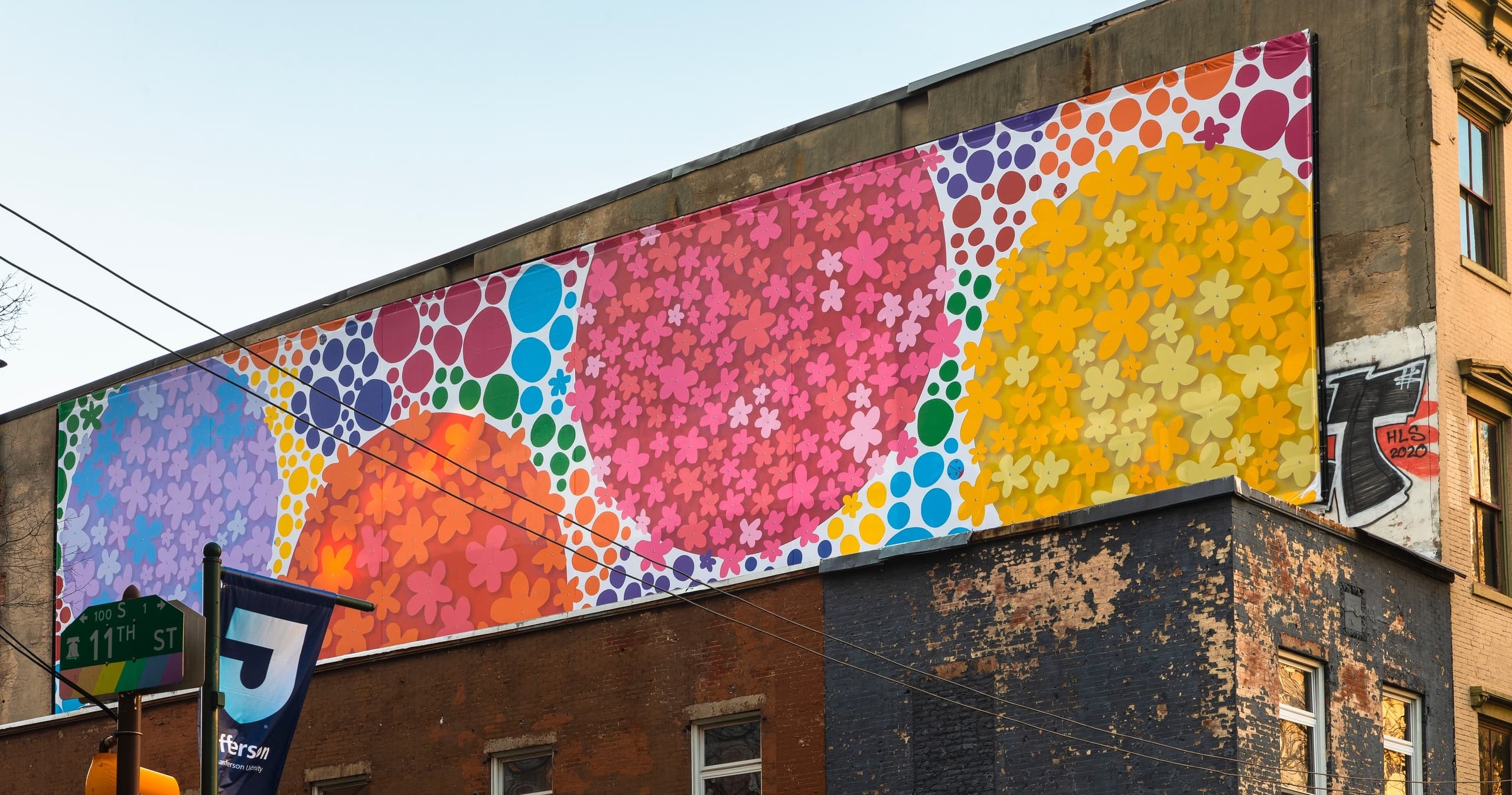 Panoramic colorful circular mural on brick building along city street