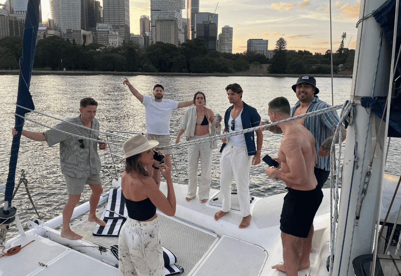Group socializing on sailboat near city skyline at dusk