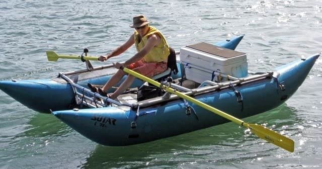 Solo paddler in inflatable cataraft navigating open river waters