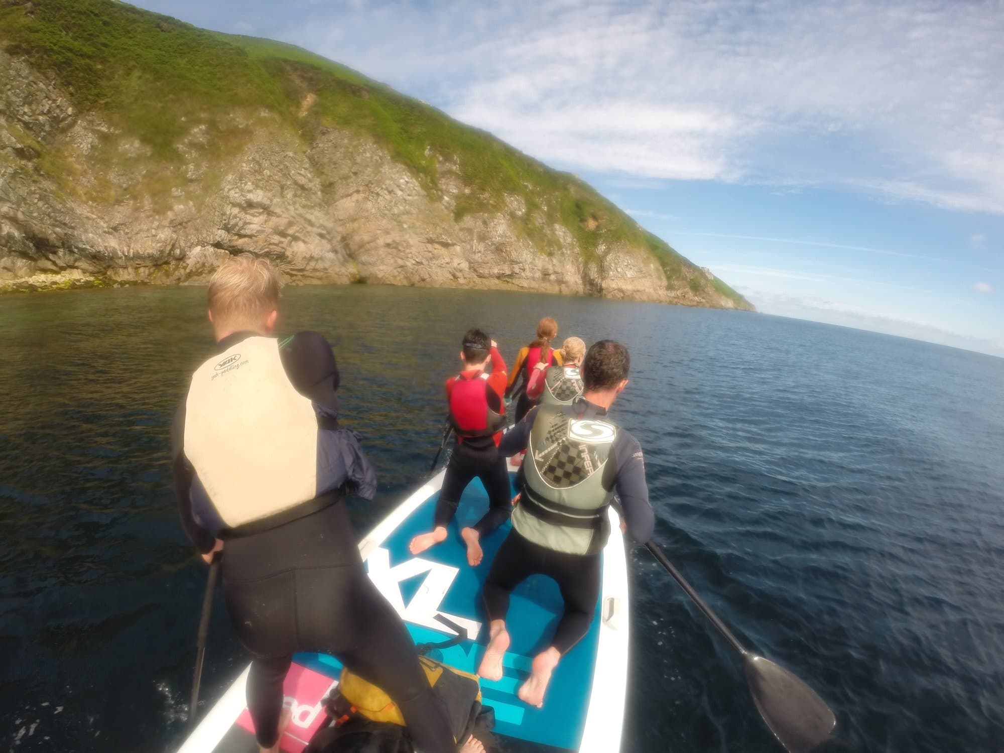 Group paddleboard tour near coastal cliffs on calm sea