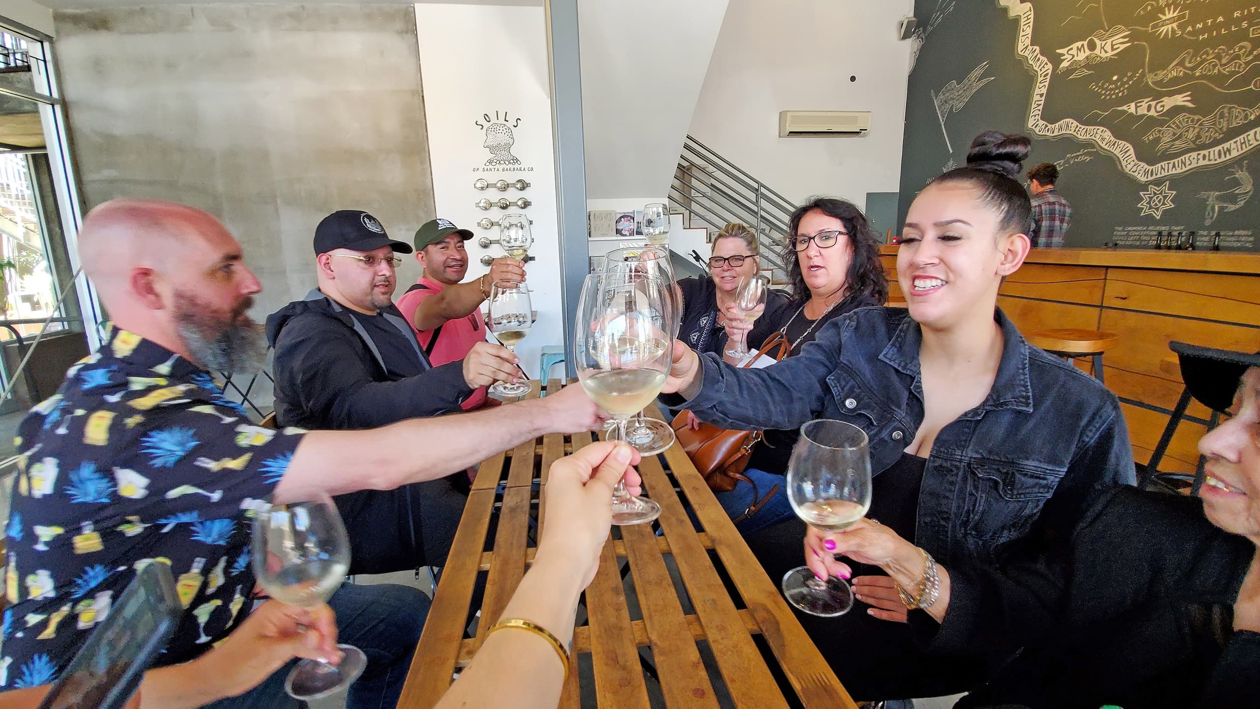 Group toasting with wine at communal tasting table in winery
