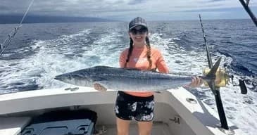 Angler holding large wahoo on a sportfishing boat in Hawaii