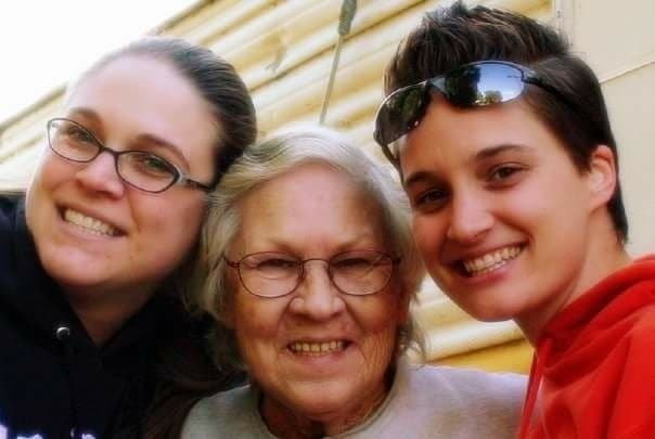 Three generations smiling outdoors with elder at family gathering