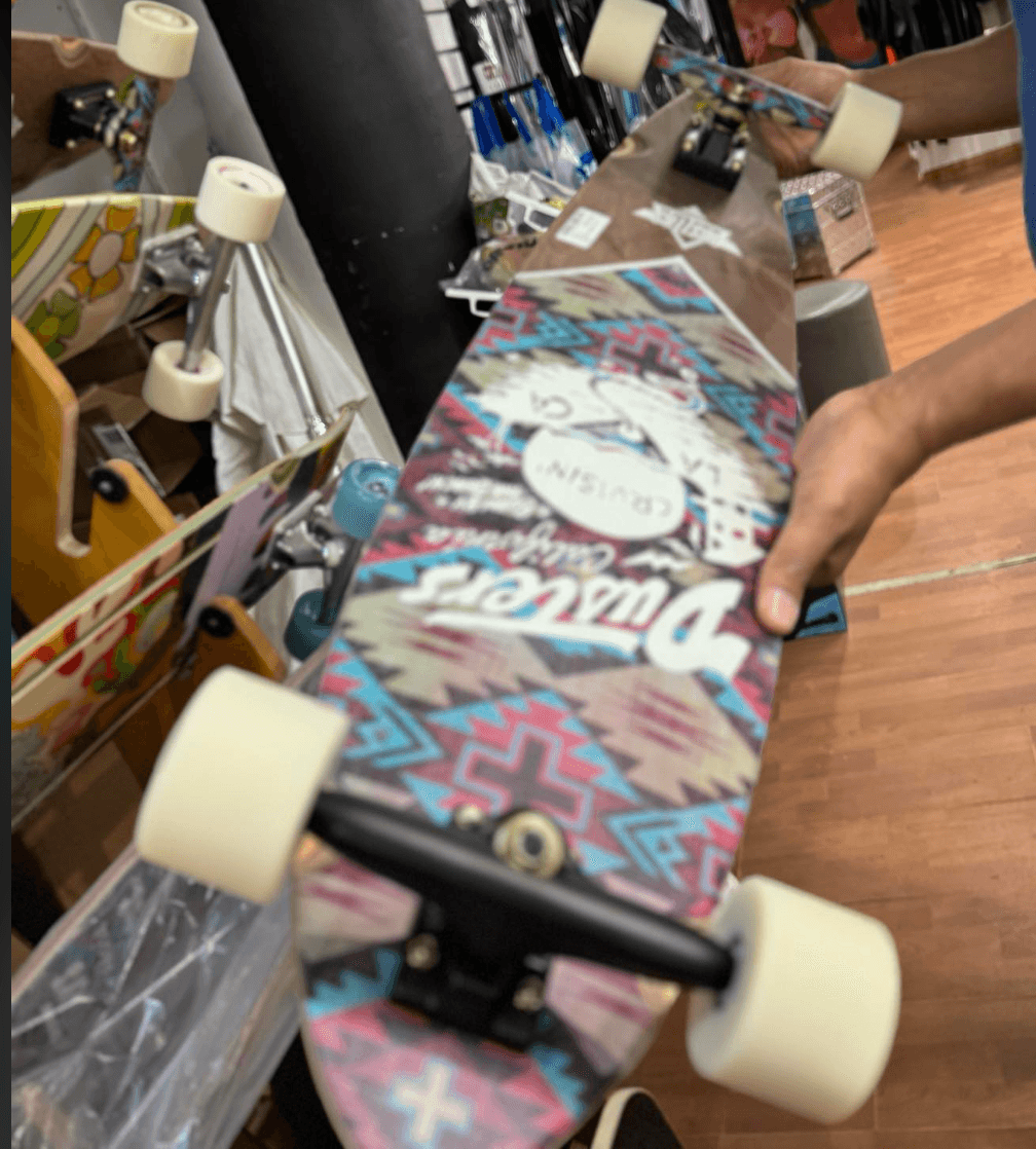 Colorful patterned longboard being held in indoor skate shop