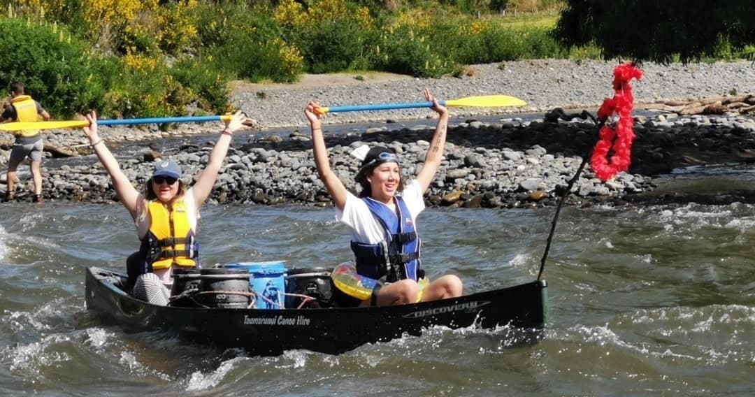 Two canoeists celebrating as they paddle through river rapids