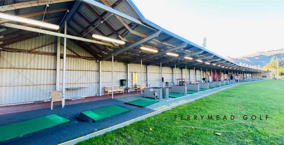 Covered driving range bays with golfers practicing shots outdoors