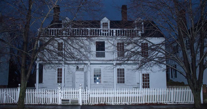 Historic colonial mansion exterior lit at night for ghost tours