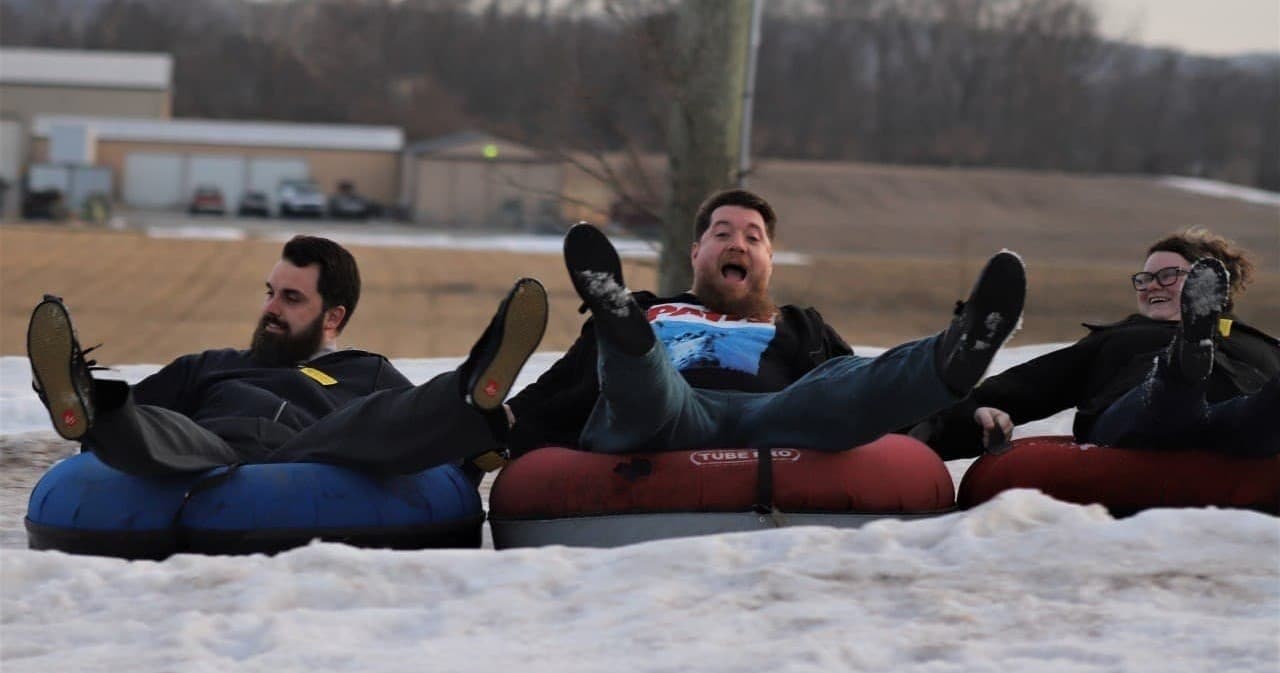 Group of friends snow tubing together on hill at tubing park