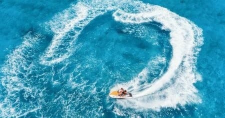 Two riders jet skiing in tropical turquoise ocean carving circular wake