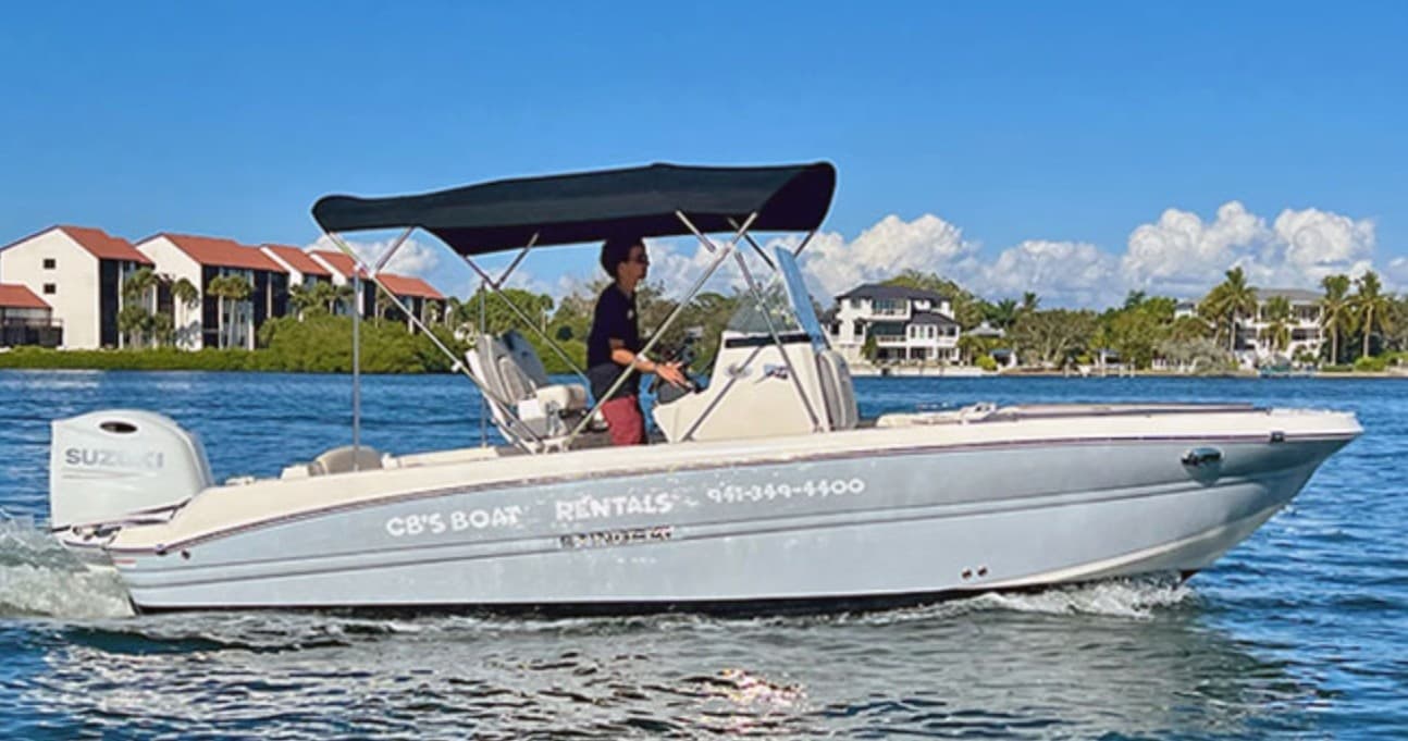 Center console motorboat cruising near shoreline, captain at helm