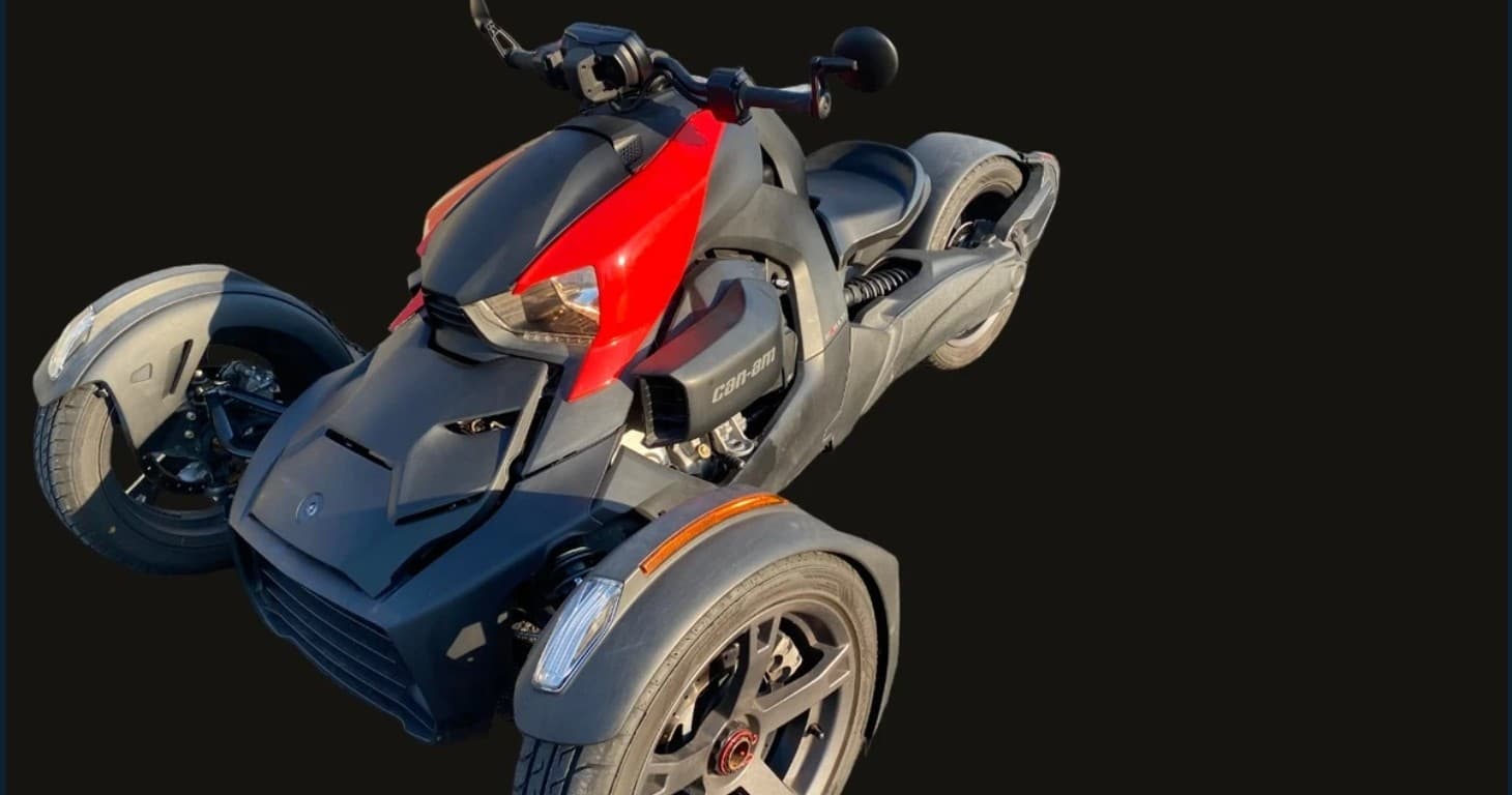 Red-accent three-wheeler roadster on dark backdrop, ready for rides