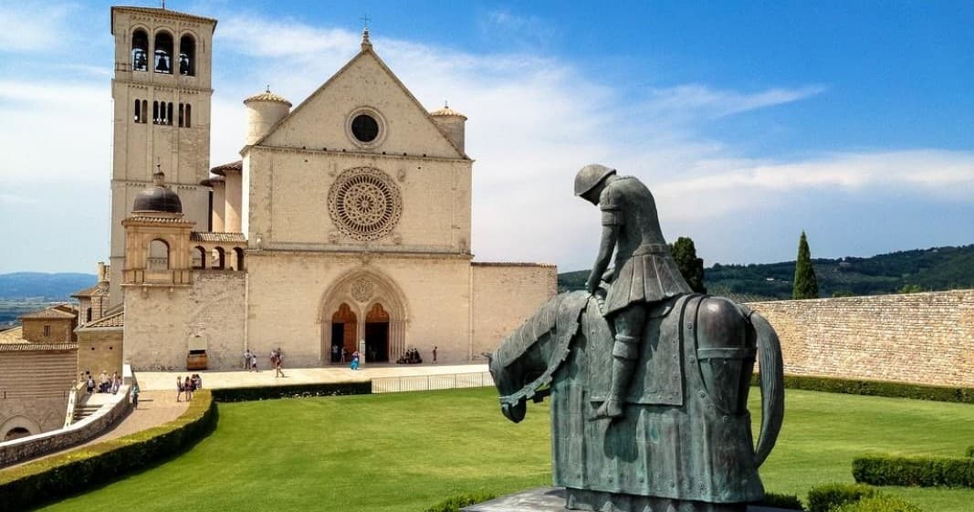 Saint Francis statue with Basilica facade in Assisi, Umbria