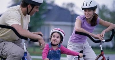 Family bike ride with child learning to pedal in park neighborhood