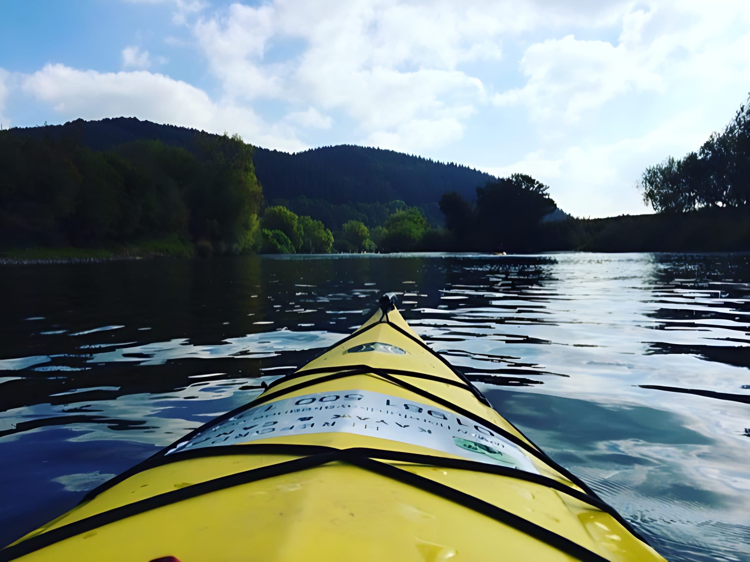 Yellow kayak bow on serene river, scenic paddling view