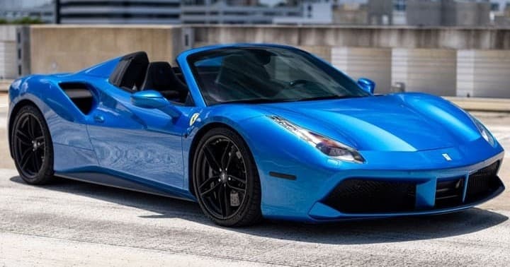 Blue Ferrari convertible parked on urban waterfront, driving-ready
