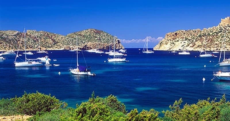 Scenic bay with multiple sailboats anchored, Mallorca harbor view