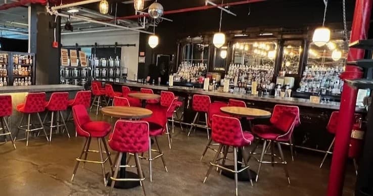 Cocktail bar interior with red velvet seats and stocked back bar