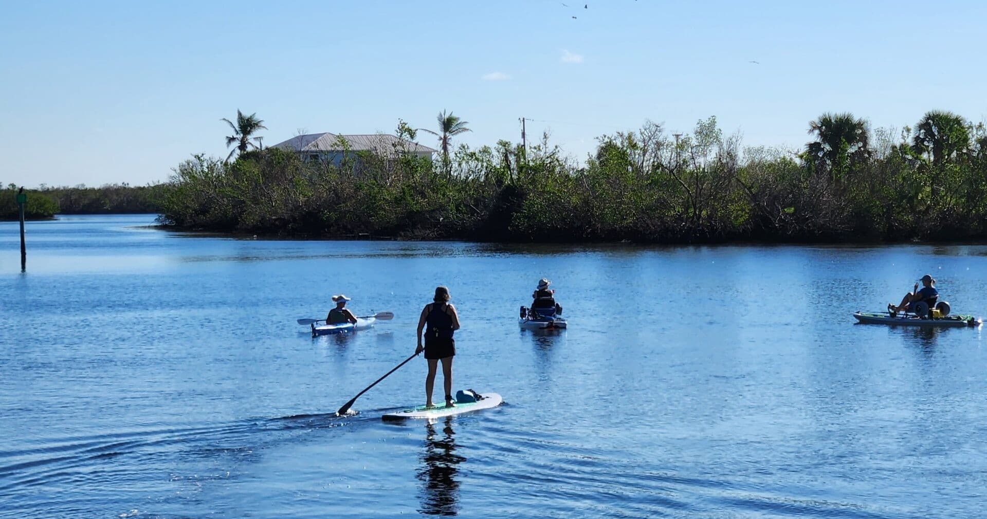 Stand-up paddlers and kayakers touring calm coastal lagoon