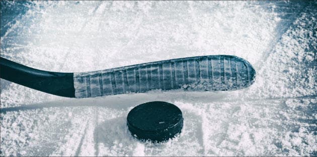 Hockey stick and puck on textured ice, close-up indoor rink