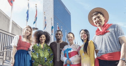 Diverse travelers posing outside United Nations building with flags