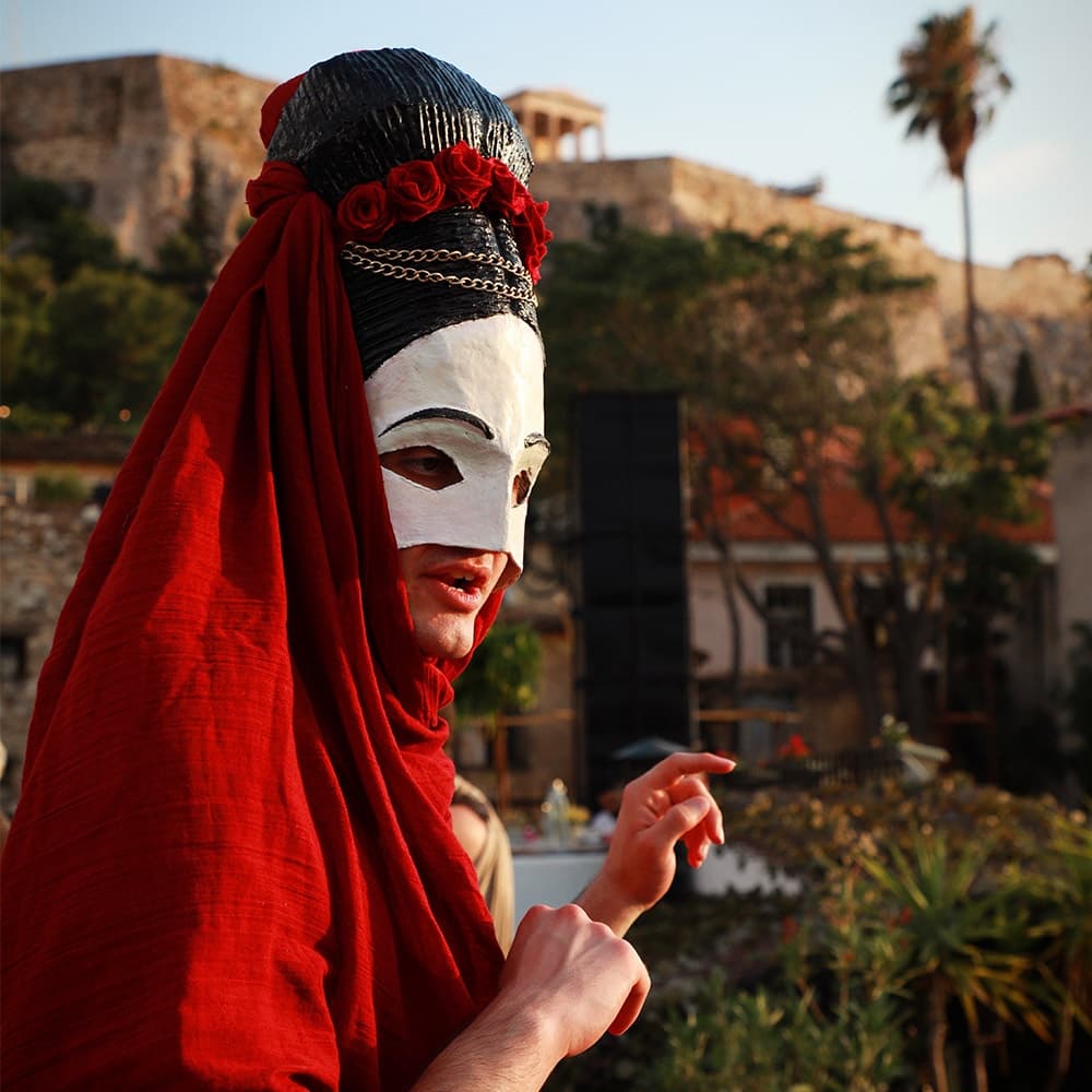 Masked street performer in red robe at historic coastal fortress