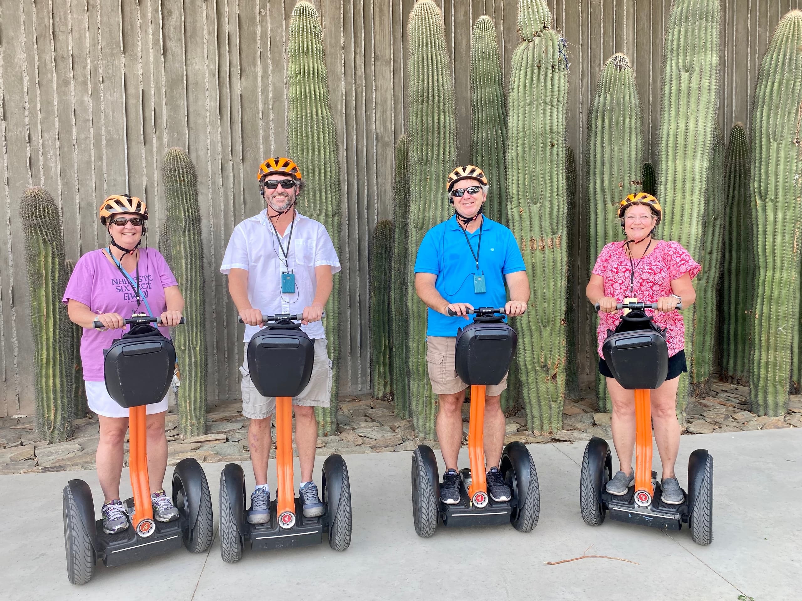 Four Segway riders posing by tall cactus on desert tour