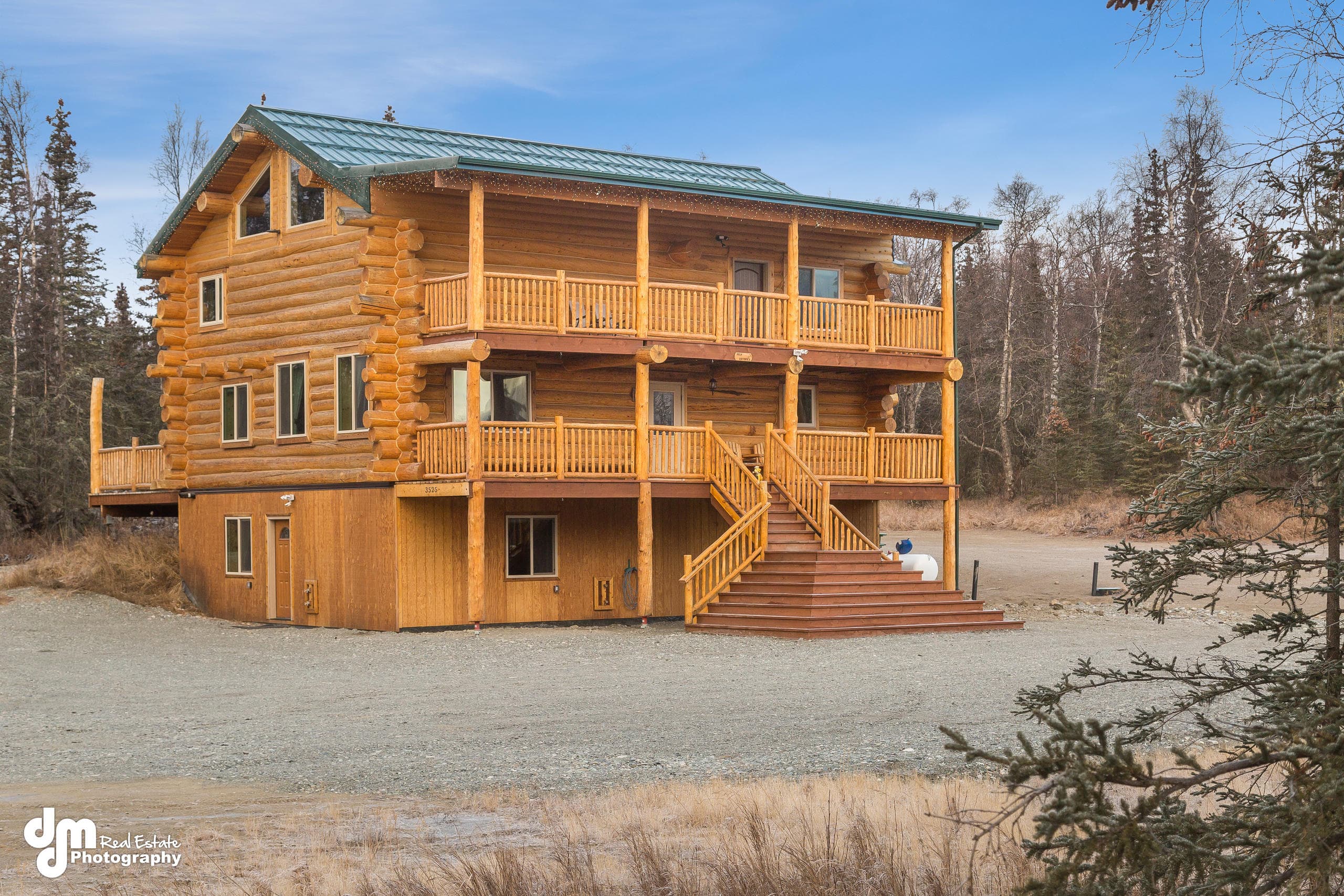 Wide-angle exterior of multi-level knotty pine lodge in Alaskan woods