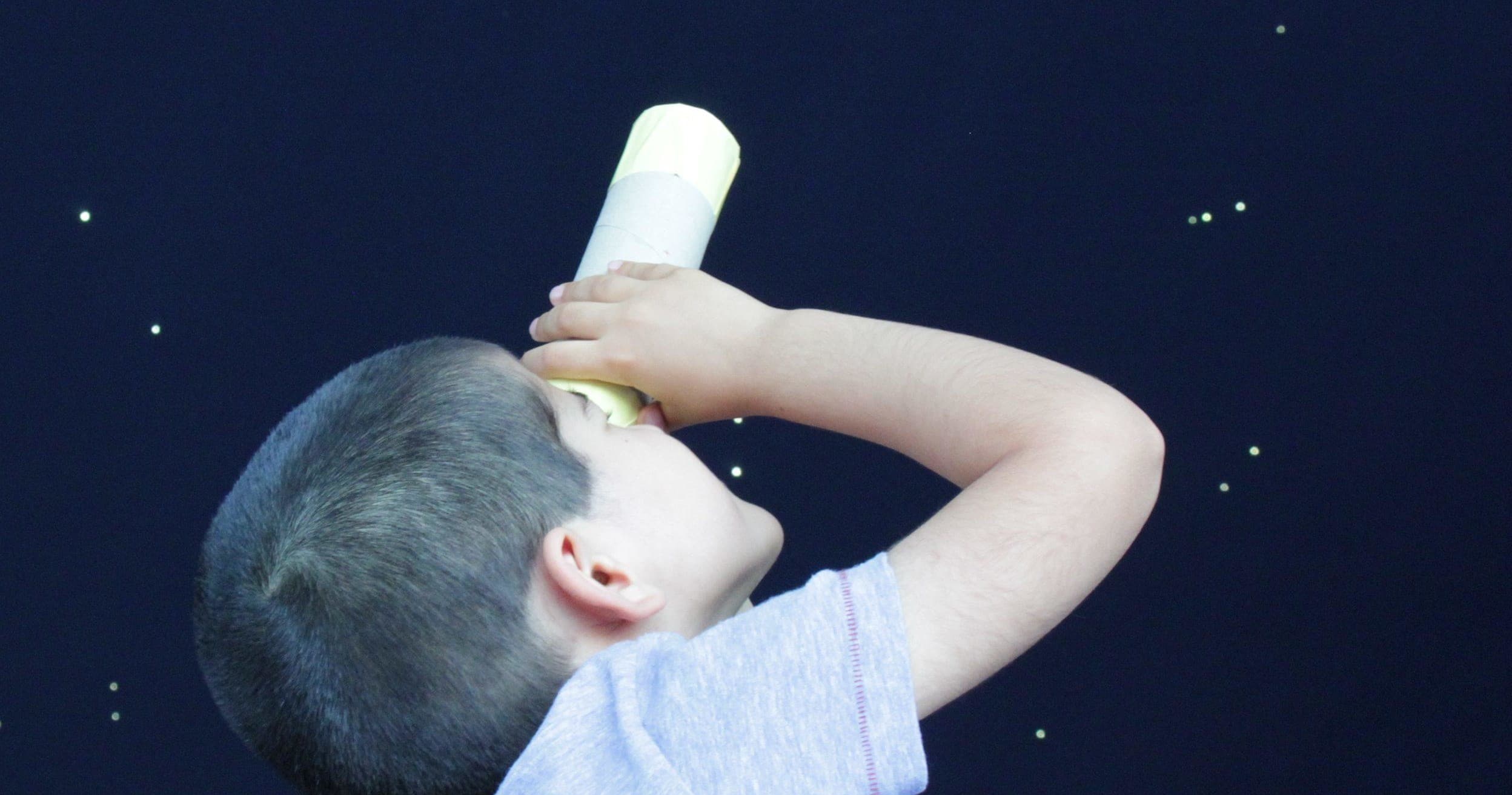 Child looking through telescope at night sky for stargazing
